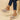 Pink women's espadrille wedge sandals with suede strap and ankle chain displayed on a model's foot, highlighting the combination of casual style with elegant detailing.