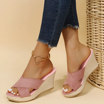 Pink women's espadrille wedge sandals featuring a suede strap and an ankle chain, worn on a leg.