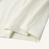 Plain white unisex t-shirt with short sleeves and a round collar, minimalist design shown on a beige background.