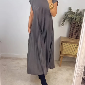 Pleated maxi dress in taupe with cap sleeves, worn by a woman accessorized with sunglasses; the dress features a fitted waist and flows elegantly to the knees, suitable as a summer women's day dress in a gray 3XL size.