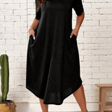 Plus size black loose fit midi dress with short sleeves and a round neck, designed for a casual summer look. The dress is oversized and falls to a mid-length, offering a comfortable and fashionable fit for size 2XL. The model is standing, showcasing the dress's relaxed style.