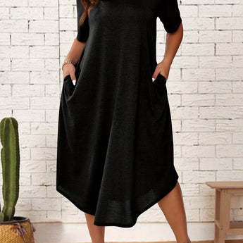 Plus size black loose fit midi dress with short sleeves and a round neck, designed for a casual summer look. The dress is oversized and falls to a mid-length, offering a comfortable and fashionable fit for size 2XL. The model is standing, showcasing the dress's relaxed style.