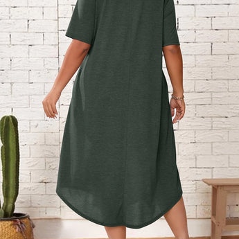 
A woman standing and wearing a plus size green loose fit midi dress, ideal for casual summer wear. The dress features an oversized design with comfortable sleeves and a relaxed waistline, falling to a knee-length.