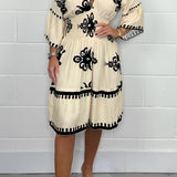 Plus size white V-neck boho summer dress with floral embroidery, featuring short sleeves and a flowing knee-length design.