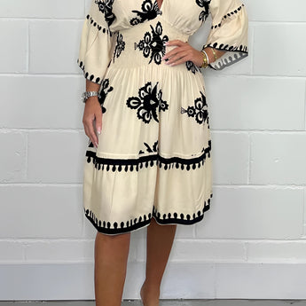 Plus size white V-neck boho summer dress with floral embroidery, featuring short sleeves and a flowing knee-length design.