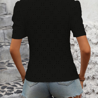 A woman wearing a trendy white polka dot blouse with short sleeves, styled for a casual chic summer look.