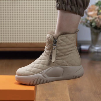 Quilted waterproof winter boots for women in khaki, size 42, featuring a cushioned sole. The boots are displayed on a wooden floor near a flowerpot.