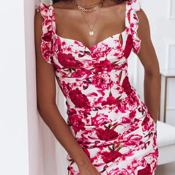 
A woman wearing a sleeveless red floral ruffle dress, styled with a white rose pattern, in a size XXL. The dress is a designer cocktail attire, highlighting the shoulders and flowing elegantly down the body.