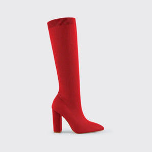 Red knee-high sock boots featuring a high heel and ribbed fabric texture, worn by a model showcasing fashionable footwear.