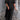 
A person wearing a black red maxi dress with puff sleeves, a square neckline, and studded pockets, standing and smiling with their hands on their waist.