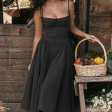 Red spaghetti strap midi dress in a vintage tea style, displayed outdoors on grass with a wooden backdrop, designed for a formal or daytime event.