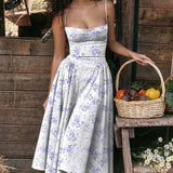 
A red midi dress in a vintage tea dress style featuring spaghetti straps and a fitted waist, modeled in an indoor setting.