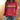 A person wearing a red multicolor striped crewneck sweatshirt paired with jeans, showcasing casual autumn fashion.