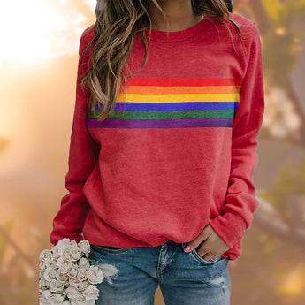 A person wearing a red multicolor striped crewneck sweatshirt paired with jeans, showcasing casual autumn fashion.