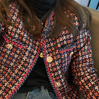 Red and navy fringed women's tweed jacket with a chic designer style, featuring a textured pattern, long sleeves, and a structured collar.