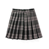 Red plaid pleated tartan skirt styled as a preppy schoolgirl mini kilt, featuring a classic plaid pattern and pleats, worn by a person standing outdoors near trees.