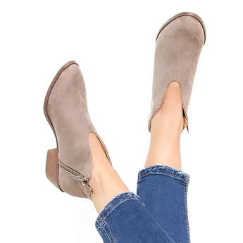 Gray suede pointed toe women's ankle booties with a slip-on design and low heel, shown worn on a model's feet.