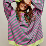 Red and white striped long sleeve crew neck blouse with button cuffs worn by a smiling person in jeans, displaying a casual and fashionable look.