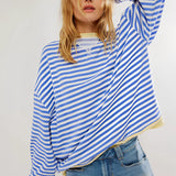 Red and white striped long sleeve crew neck blouse with button cuffs, worn by a person with shoulder-length hair, paired with shorts, showcasing a fashionable and casual look.