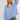 Red and white striped long sleeve crew neck blouse with button cuffs, worn by a person with shoulder-length hair, paired with shorts, showcasing a fashionable and casual look.