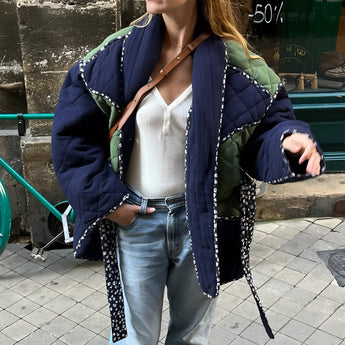 Reversible navy blue quilted kimono jacket with urban boho style, featuring long sleeves and a relaxed fit, modeled with casual jeans.
