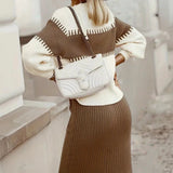 
A stylish ribbed knit dress paired with a fringe sweater, complemented by a white textured bag. The outfit is displayed on a model, highlighting the design and fit of the clothing, as well as the textured details of the bag.