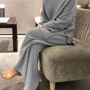Gray ribbed women's loungewear set in soft knitwear, displayed on a model standing in a cozy indoor setting with wooden flooring and a couch in the background. The outfit is in a 3XL size, emphasizing comfort and a relaxed style.