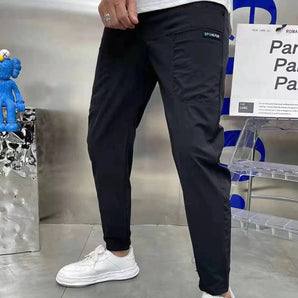 Men wearing black tapered track pants in a slim fit design, showcasing a moisture-wicking fabric, standing with visible emphasis on the waist and legs.