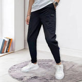 Men's black tapered track pants with a slim fit design, featuring moisture-wicking fabric. The pants are styled with a fitted waist and tailored legs, ideal for athletic or casual wear.