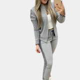 
Women's luxury tracksuit in rose gold velvet with sequin details, shown in gray color, size XL. The outfit features long sleeves, a fitted waist, and a stylish collar, accessorized with sunglasses.