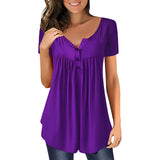 A woman wearing a purple scoop neck blouse with pleated detailing, smiling and posing, showcasing the casual summer top.