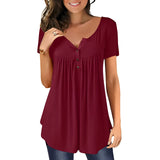 A woman smiling and wearing a royal blue pleated scoop neck blouse with short sleeves, paired with jeans.