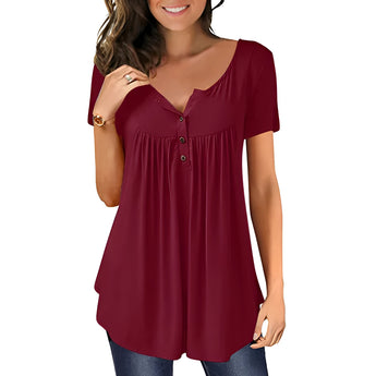 A woman smiling and wearing a royal blue pleated scoop neck blouse with short sleeves, paired with jeans.