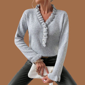 Gray knit button-up cardigan featuring a ruffled collar, shown worn by a model, highlighting the sweater's long sleeves, textured fabric, and winter fashion style.