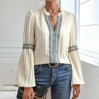 Cream ruffled blouse with a unique neckline in a boho chic and vintage-inspired style, featuring long sleeves and a relaxed fit, paired with jeans.