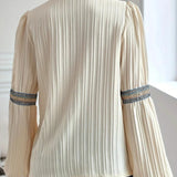 Ruffled cream blouse with a unique neckline, featuring boho chic and vintage-inspired design, characterized by its white color and long sleeves.