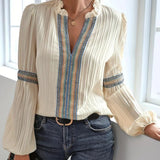 Woman wearing a ruffled cream blouse with a unique neckline, styled in a boho chic, vintage-inspired fashion.