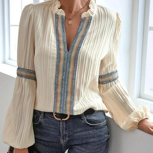 Woman wearing a ruffled cream blouse with a unique neckline, styled in a boho chic, vintage-inspired fashion.