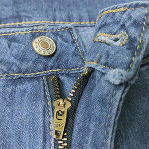 Close-up image of a rugged classic denim jacket featuring a brass zipper and metal buttons, emphasizing the electric blue denim fabric and detailed sleeve design.