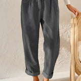 Gray high-waisted women's pleated pants in vintage style, made from corduroy fabric, worn by a person standing. The pants are designed with a focus on the waist and feature a relaxed fit around the thigh and knee areas.