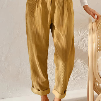 Vintage style rust corduroy high-waisted pleated women's pants in a yellow hue, shown in size 3XL, highlighting features such as the snug fit around the waist and thighs with a classic pleat design.