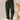 A woman standing and wearing green high-waisted pleated pants made from corduroy fabric, showcasing a vintage style.