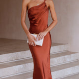 Rust satin midi slip dress with a backless tie-back design, featuring an elegant silhouette. The dress showcases a smooth satin texture, highlighting the waist and shoulder areas. It also displays a sleeveless cut with a focus on the neckline and overall elegant fit.