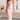 
A model wearing a pink rust satin midi slip dress with a backless design and tie-back detail, showcasing elegant wear. The dress features thin shoulder straps and a fitted waist, with the model smiling and posing to highlight the garment's shape and elegance.