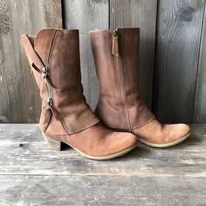 Rustic women's distressed brown leather mid-calf boots with a zipper, featuring a cowboy boot style and a textured, worn look.