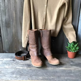 Brown distressed leather mid-calf boots with a zipper, showcasing a rustic design ideal for women's fashion. The boots are set against a wooden background.