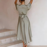 Sage green midi wrap dress featuring a V-neckline, flutter sleeves, and a high slit, shown with focus on the waist and leg area.