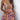 Woman wearing an orange sequin skater skirt and backless halter top, posing with one arm on her hip and the other by her side, suitable for festivals and parties.