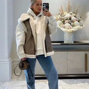 Sherpa fleece vest with buckle worn by a woman styled with jeans, showcasing a casual streetwear look with eyewear, highlighting a white dress shirt underneath the vest, standing confidently displaying the garment's texture and design.
