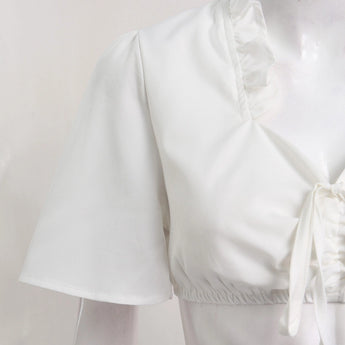 Short white dirndl blouse with a chic cropped design, featuring a tie-front, ruffled neckline, and short sleeves, suitable for formal or fashion-forward occasions.